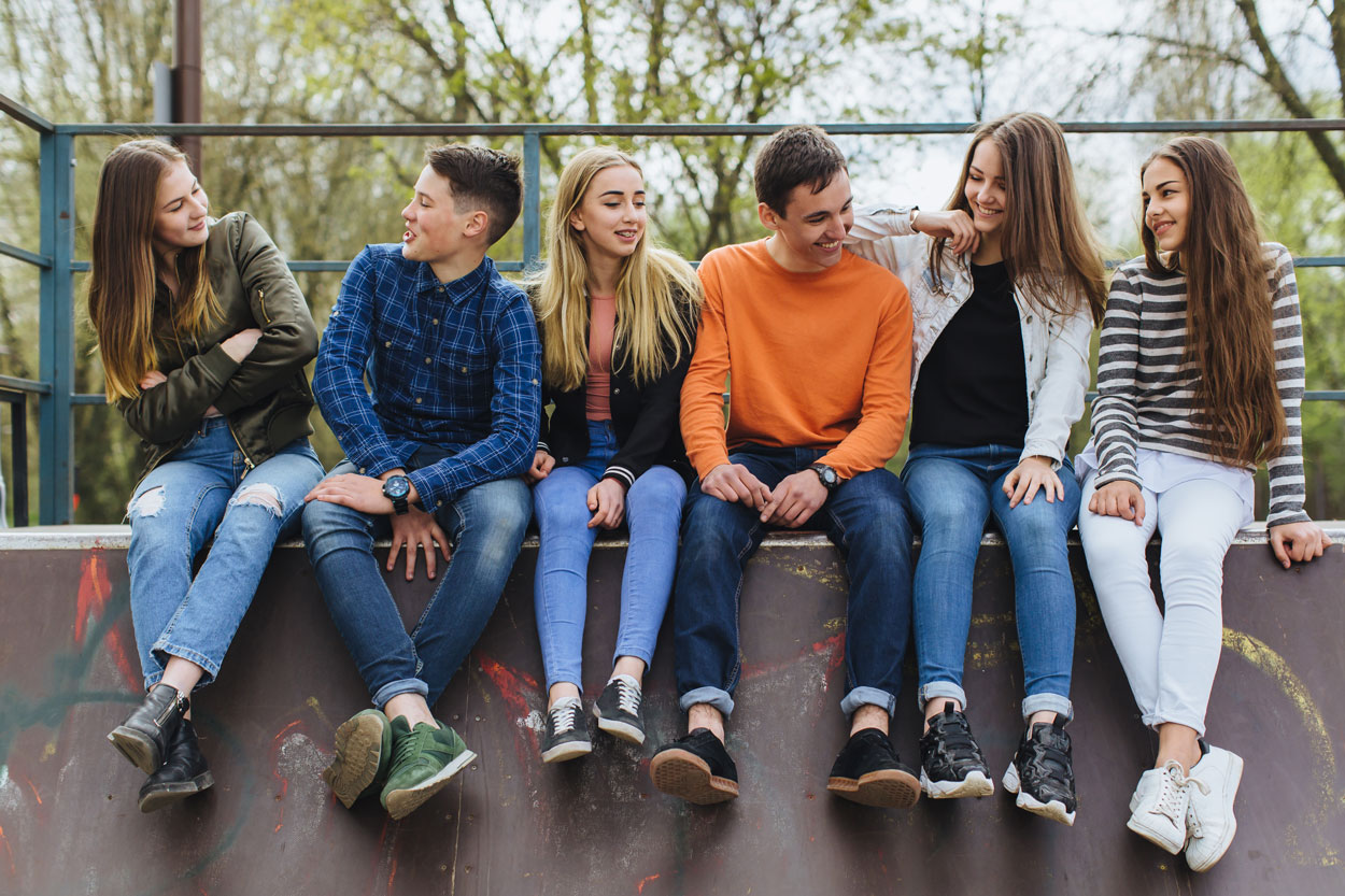 five teenagers sitting on wall